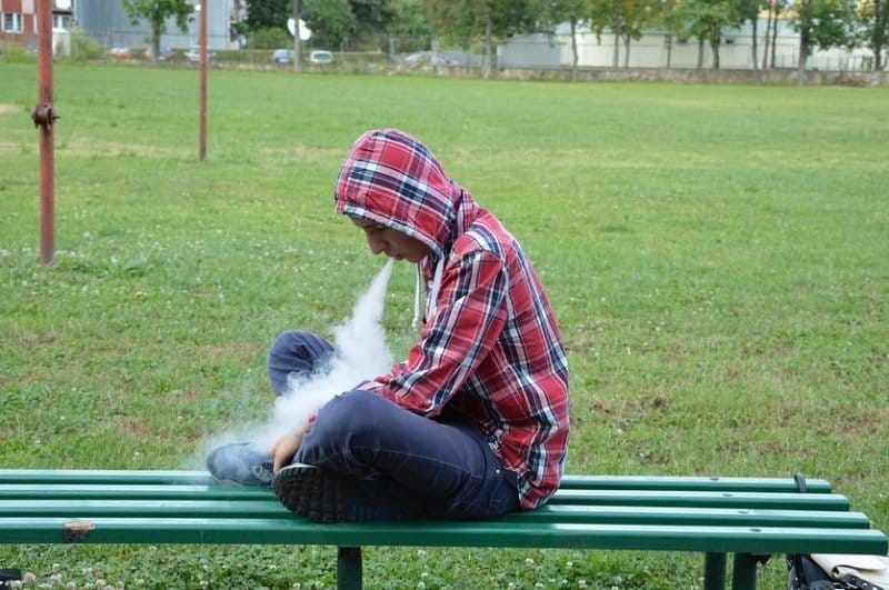 guy vaping on park bench